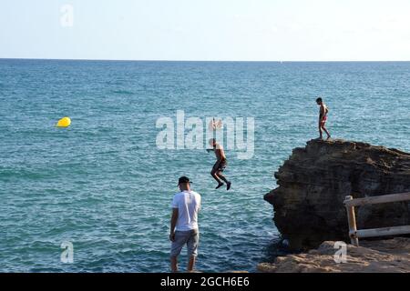 Roda de Bara, Espagne. 05 août 2021. Un jeune homme plonge dans la mer depuis une falaise à la plage du Roc de Sant Gaieta à Roda de Bara.les jeunes sautent des falaises à la plage du Roc de Sant Gaieta à Roda de Bara (Tarragone Espagne), une pratique qui est interdite, dangereux et peut causer de graves blessures corporelles et même la mort par l'impact contre les roches. Crédit : SOPA Images Limited/Alamy Live News Banque D'Images