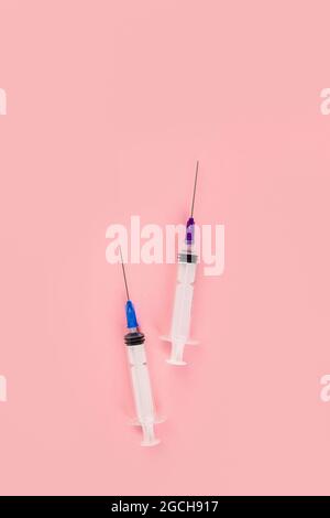 Seringues placées sur fond rose. Concept médical et vaccination. Vue de dessus, plat, espace de copie Banque D'Images