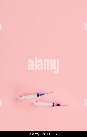 Seringues placées sur fond rose. Concept médical et vaccination. Vue de dessus, plat, espace de copie Banque D'Images