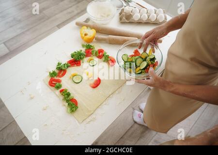 Gros plan sur la préparation de la pizza végétalienne par la mère et la fille dans la cuisine Banque D'Images