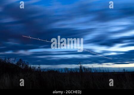 Lumières de nuit, pistes de lumière dans le mouvement de l'avion en exposition longue Banque D'Images