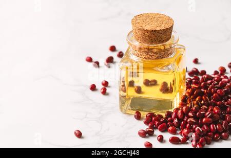Bouteille en verre d'huile essentielle avec un tas de haricots rouges sur le sol en marbre de verre, courte et grasse dans une bouteille en verre de forme carrée avec de l'huile essentielle, bla Banque D'Images