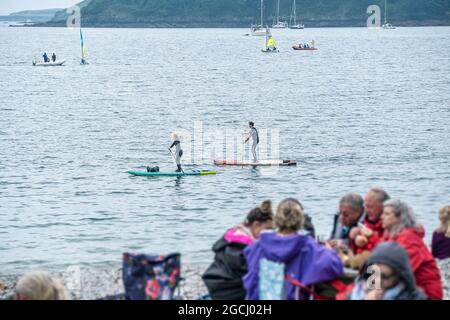 Les vacanciers sur les paddleboards Stand Up en passant par Polgwidden Cove sur le passage Helford River lors d'une journée froide à Cornwall. Banque D'Images