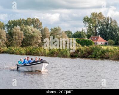 Groupe de personnes naviguant dans un petit bateau en boucle sur le canal près de Grouw, à Friesland, aux pays-Bas Banque D'Images