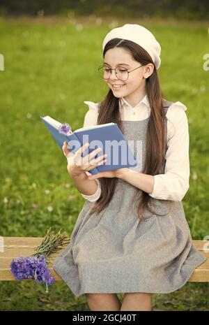 Élégante écolière enfant fille lisant le livre dans le parc, concept de langue française Banque D'Images