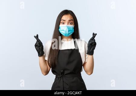 Covid-19, distanciation sociale, petite entreprise de café et prévention du virus concept. Inquiet plein d'espoir propriétaire de café asiatique, j'espère avoir des visiteurs, traverser Banque D'Images