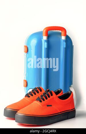 Valise bleue et gumShoes orange sur fond blanc. Concept de voyage. Copier l'espace Banque D'Images