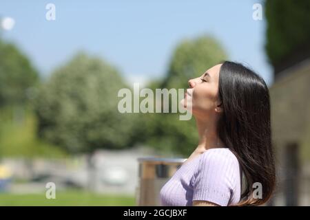 Profil d'une femme asiatique respirant de l'air frais dans un parc un jour ensoleillé Banque D'Images