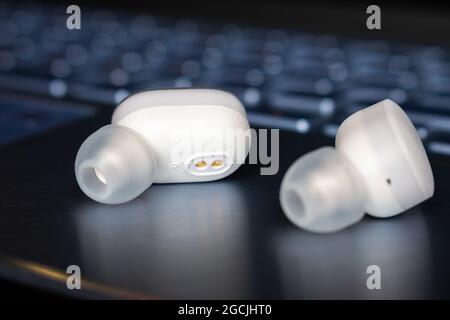 casque bluetooth sans fil en gros plan sur l'arrière-plan de l'ordinateur portable Banque D'Images