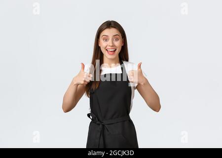 Concept des employés d'épicerie, des petites entreprises et des cafés. Une femme de barista enthousiaste et joyeuse se montre très enthousiaste. Vendeur noir Banque D'Images