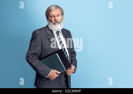 Portrait de l'homme à tête grise aîné, professeur, enseignant travaillant au travail, à l'intérieur. Concept de profession, d'emploi, d'éducation et de motivation professionnels. Banque D'Images