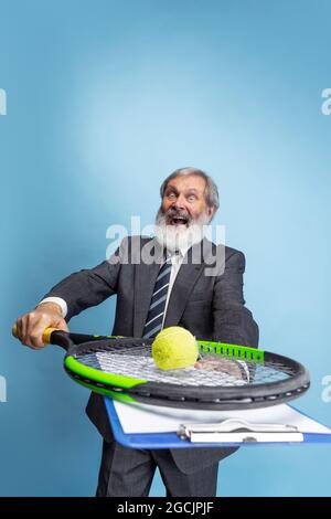 Portrait de l'homme à tête grise aîné, professeur, enseignant travaillant isolé sur fond bleu de studio. Concept de profession professionnelle, emploi, éducation Banque D'Images