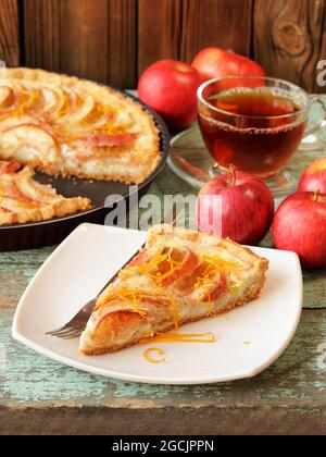 Tarte aux pommes maison à la crème sure avec thé noir et pommes fraîches entières verticales Banque D'Images