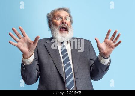 Un professeur fou, un professeur, un homme barbu à tête grise qui se pose isolé sur fond de studio gris. Concept de profession professionnelle, emploi, éducation, drôle Banque D'Images