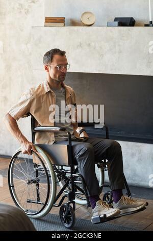 Portrait vertical complet d'un homme adulte moderne en fauteuil roulant à la maison Banque D'Images