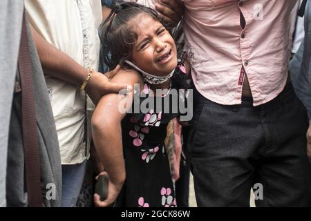 Non exclusif: DHAKA, BANGLADESH - AOÛT 7: Un enfant désarpe, alors que voir comme sont livrés les restes dans les cercueils, des parents qui sont morts dans la dea Banque D'Images