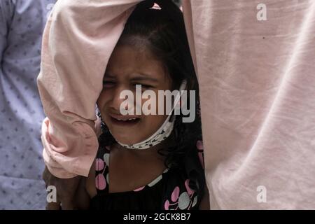 Non exclusif: DHAKA, BANGLADESH - AOÛT 7: Un enfant désarpe, alors que voir comme sont livrés les restes dans les cercueils, des parents qui sont morts dans la dea Banque D'Images