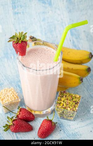 Smoothie froid aux fraises et aux bananes sur fond bleu Banque D'Images