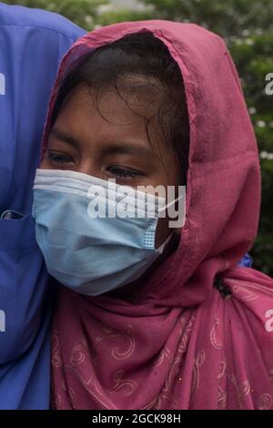 Non exclusif: DHAKA, BANGLADESH - AOÛT 7: Un enfant désarpe, alors que voir comme sont livrés les restes dans les cercueils, des parents qui sont morts dans la dea Banque D'Images