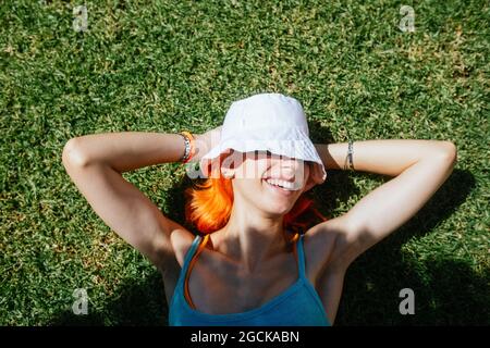 Vue de dessus d'une jeune femme joyeuse à tête rouge, couché sur l'herbe par une belle journée d'été Banque D'Images
