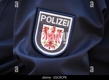 Potsdam, Allemagne. 09e août 2021. Logo de la police de Brandebourg avec aigle rouge et inscription sur la manche de la veste d'une femme policier. Credit: Soeren Stache/dpa-Zentralbild/dpa/Alay Live News Banque D'Images