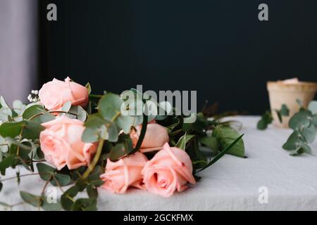 Bouquet de roses roses avec des feuilles vertes couchés sur une table blanche Banque D'Images