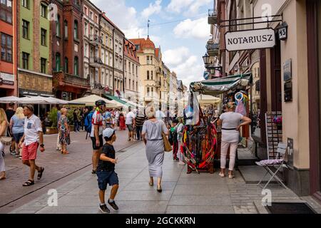 TORUN, POLOGNE - 22 juillet 2021 : beaucoup de gens marchent dans une rue entre des bâtiments avec des restaurants et des magasins dans le centre-ville Banque D'Images