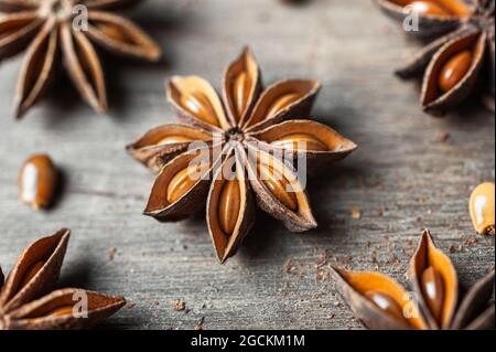 Gros plan sur des étoiles d'anis séchées aromatiques avec des graines éparpillées sur une table en bois rustique pour le concept gastronomique de fond Banque D'Images