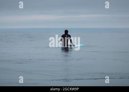 30 avril 2021. Anapa, Russie. Surfeur en combinaison assis à la planche de surf en mer et en vague d'attente Banque D'Images