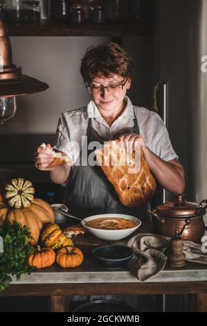 Femme souriante tenant du pain pour la soupe à la crème de citrouille d'automne Banque D'Images