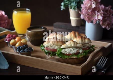 Délicieux croissants avec légumes servis sur plateau avec cappuccino et jus d'orange préparés pour le petit déjeuner français et placés sur du tabl en bois Banque D'Images