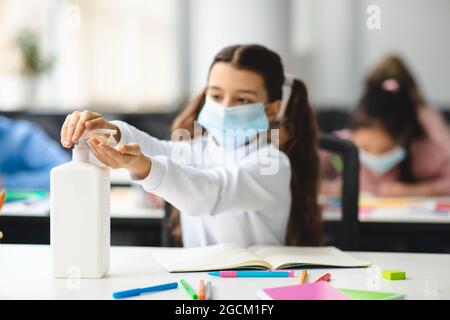 Pupille féminine appliquant un désinfectant antibactérien sur les mains Banque D'Images