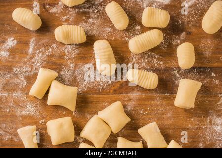 De dessus vue de dessus de dessus de gnocchi non cuits placés dans les rangées sur la table de bois pendant la préparation du déjeuner à la maison Banque D'Images