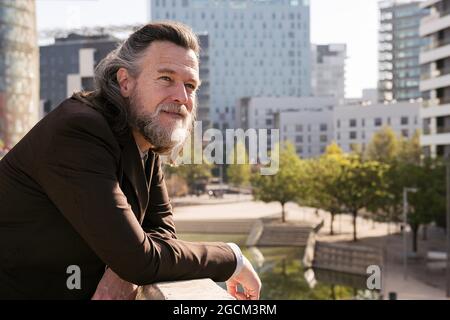 Vue latérale d'un homme à poil dur gris d'âge moyen dans une tenue élégante et habillée qui donne sur la clôture sur la terrasse de la ville b Banque D'Images