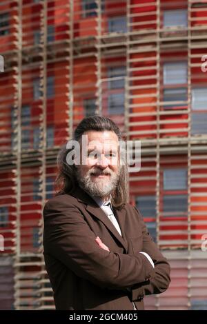 Vue latérale d'un homme à barbe d'âge moyen positif dans une tenue de style professionnel debout avec les bras croisés et regardant la caméra pensivement contre le bâtiment urbain Banque D'Images