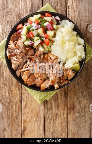 Le mijoteuse de style hawaïen Kalua porc servi avec du chou en sauce et de la salade fraîche dans la plaque d'ardoise sur la table. Vue verticale du dessus Banque D'Images