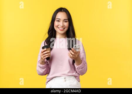 Les émotions des gens, le style de vie, les loisirs et la beauté concept. Attrayante étudiante féminine, jeune fille d'université boire un café à emporter et vérifier les messages sur Banque D'Images