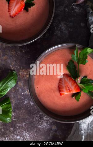 Vue de dessus des bols avec de la soupe fraîche de gaspacho aux fraises placée sur une table sombre Banque D'Images