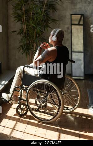 Portrait vertical de la femme moderne tatouée avec un handicap écoutant de la musique tout en se relaxant à la maison Banque D'Images