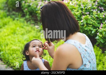 Femme mettant le maquillage sur le visage de la petite fille. Banque D'Images