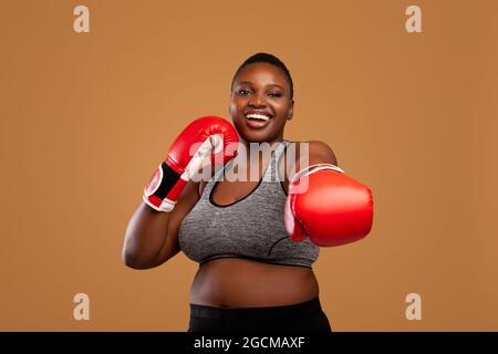 Jeune femme noire posant avec des gants de boxe au studio Banque D'Images