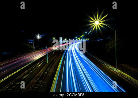 Sentiers légers sur une autoroute de chaque côté des voies ferrées la nuit, Perth, Australie occidentale, Australie Banque D'Images