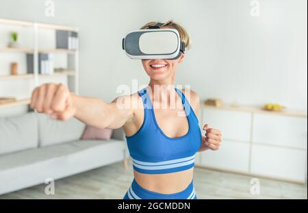 Femme dans un casque VR qui fait de l'exercice à la maison Banque D'Images