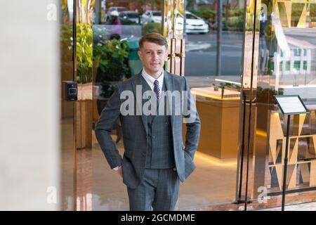 Portrait d'un jeune homme d'affaires élégant portant un costume gris classique debout près d'un bâtiment moderne. Mains dans ses poches. Photo de haute qualité Banque D'Images