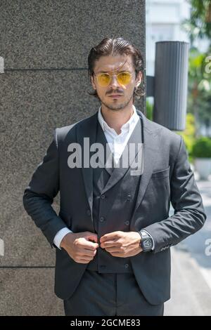 Portrait de l'homme réussi en costume noir formel et lunettes de soleil jaunes . Photo de haute qualité Banque D'Images