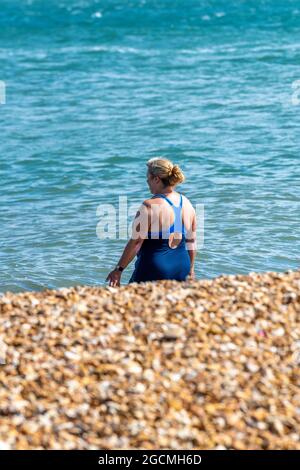 nageur sauvage sur une plage de sable, nageur sauvage sur le rivage. femme adulte nageur sauvage, femme d'âge moyen se préparant à nager, bienfaits de la natation sauvage. Banque D'Images