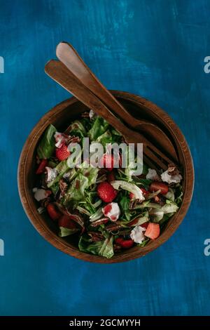 Une salade de laitue romaine avec des fruits frais et des noix et du fromage de chèvre dans un bol en bois sombre Banque D'Images