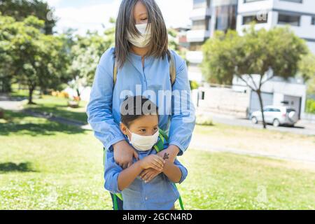 Portrait d'une fille blonde avec son frère portant des sacs à dos et un masque. Retour à l'école Banque D'Images