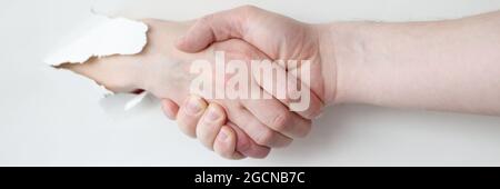 Deux personnes secouent les mains par le trou du livre blanc Banque D'Images