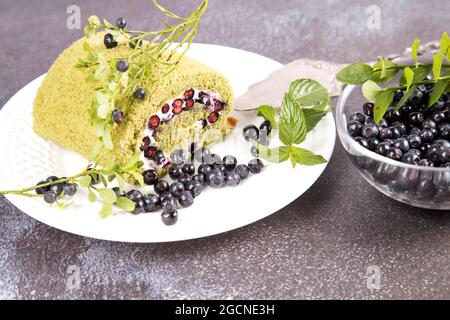 Sur fond gris, une assiette avec un rouleau d'éponge avec du thé matcha et des bleuets. Banque D'Images